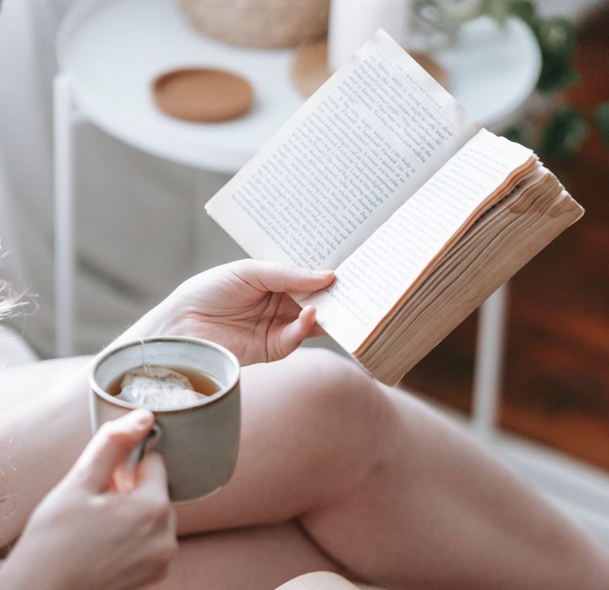 woman reading book and drinking tea at home